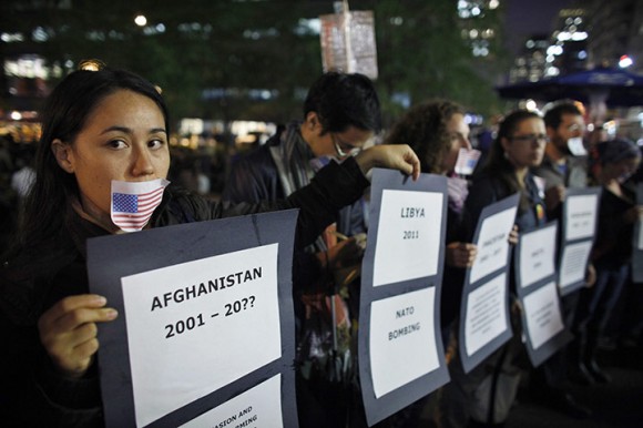 Manifestantes com uma bandeira dos EUA  anexado à boca, segurando cartazes em Zuccotti Park, perto de Wall Street, em Nova York.  Foto: Reuters